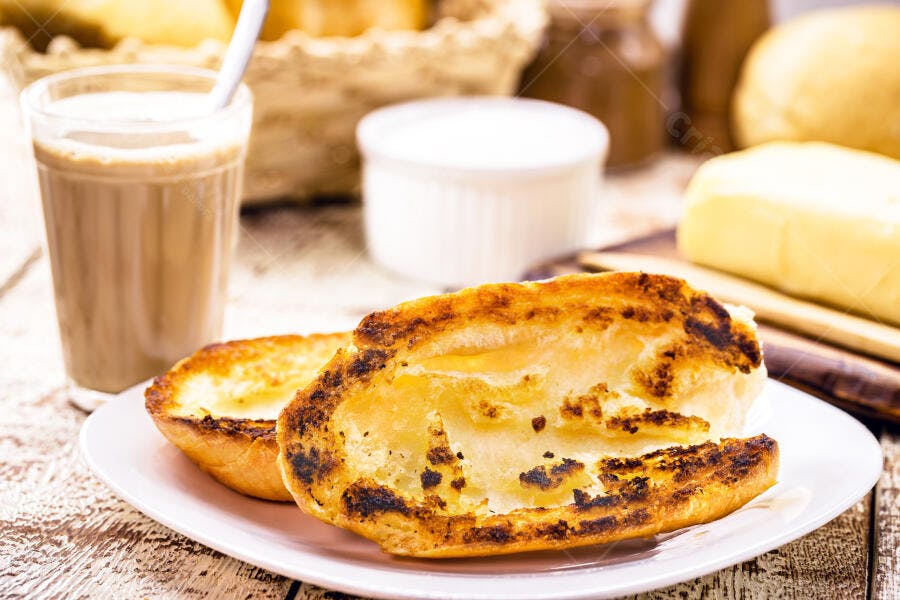 Pão na chapa torrado com café com leite e manteiga no café da manhã