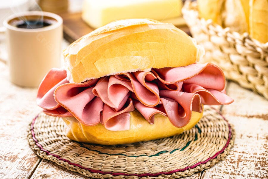 Pão francês com mortadela fatiada café e queijo fresco na mesa rústica