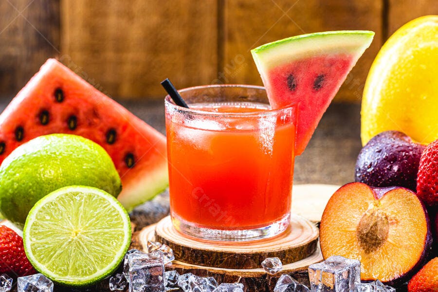 Suco refrescante de melancia e frutas tropicais com gelo em madeira rústica