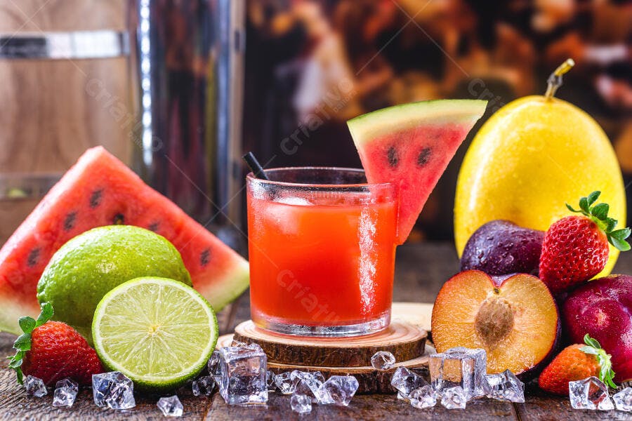 Suco de frutas vermelhas gelado com melancia limão morangos e gelo em madeira rústica