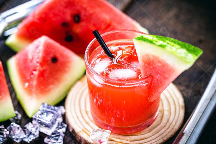 Suco de melancia gelado com fatias frescas e cubos de gelo em fundo de madeira