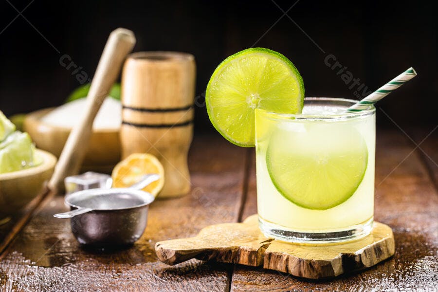 Coquetel de limão com canudo e fatias de fruta em mesa de madeira rústica