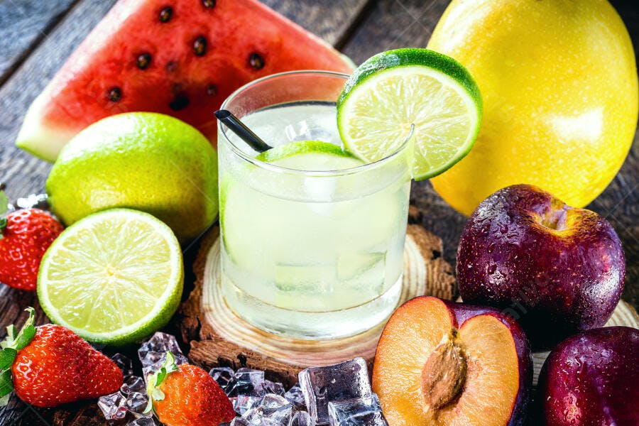 Caipirinha de limão com frutas frescas variadas em mesa de madeira rústica