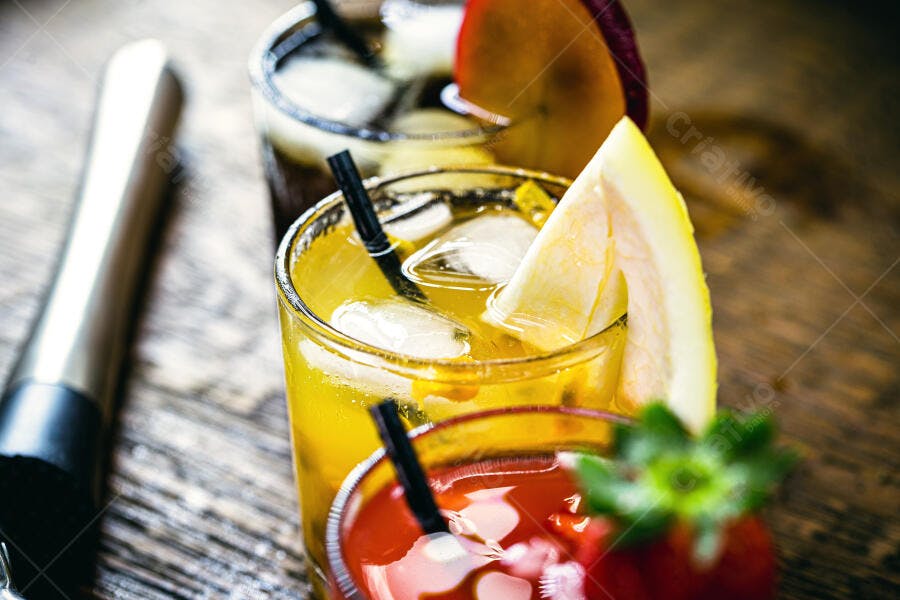 Coquetéis coloridos de frutas frescas com gelo em mesa de madeira