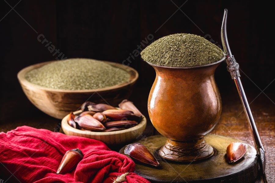 Chimarrão tradicional erva-mate e pinhão em cuia de porongo sobre madeira