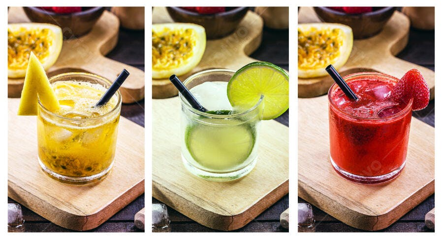 Três caipirinhas coloridas de maracujá limão e morango em tábua de madeira