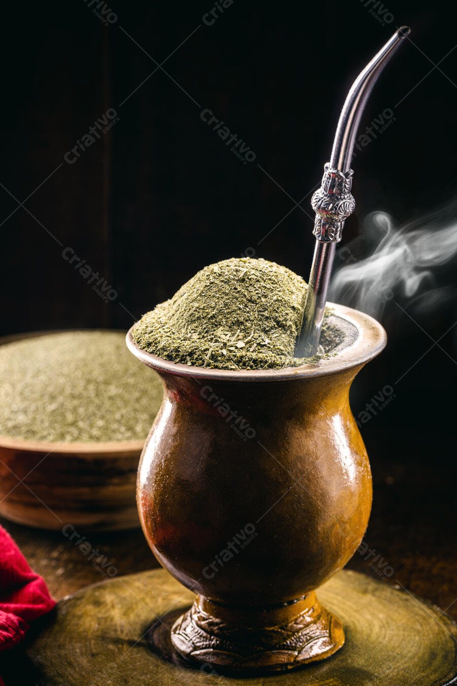 Cuia de chimarrão cheia de erva-mate e bomba com vapor em fundo escuro