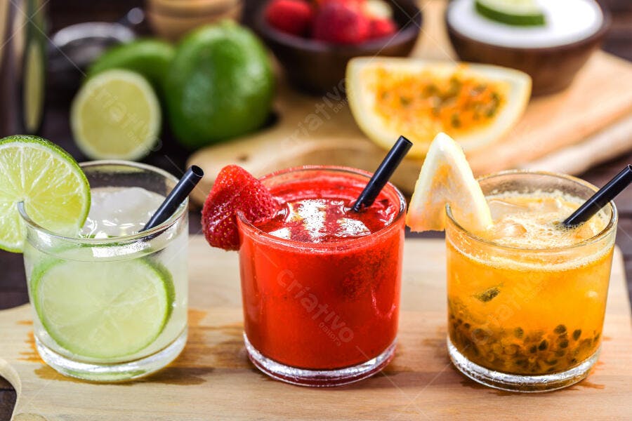 Drinks coloridos de frutas frescas com limão, morango e maracujá em mesa de madeira