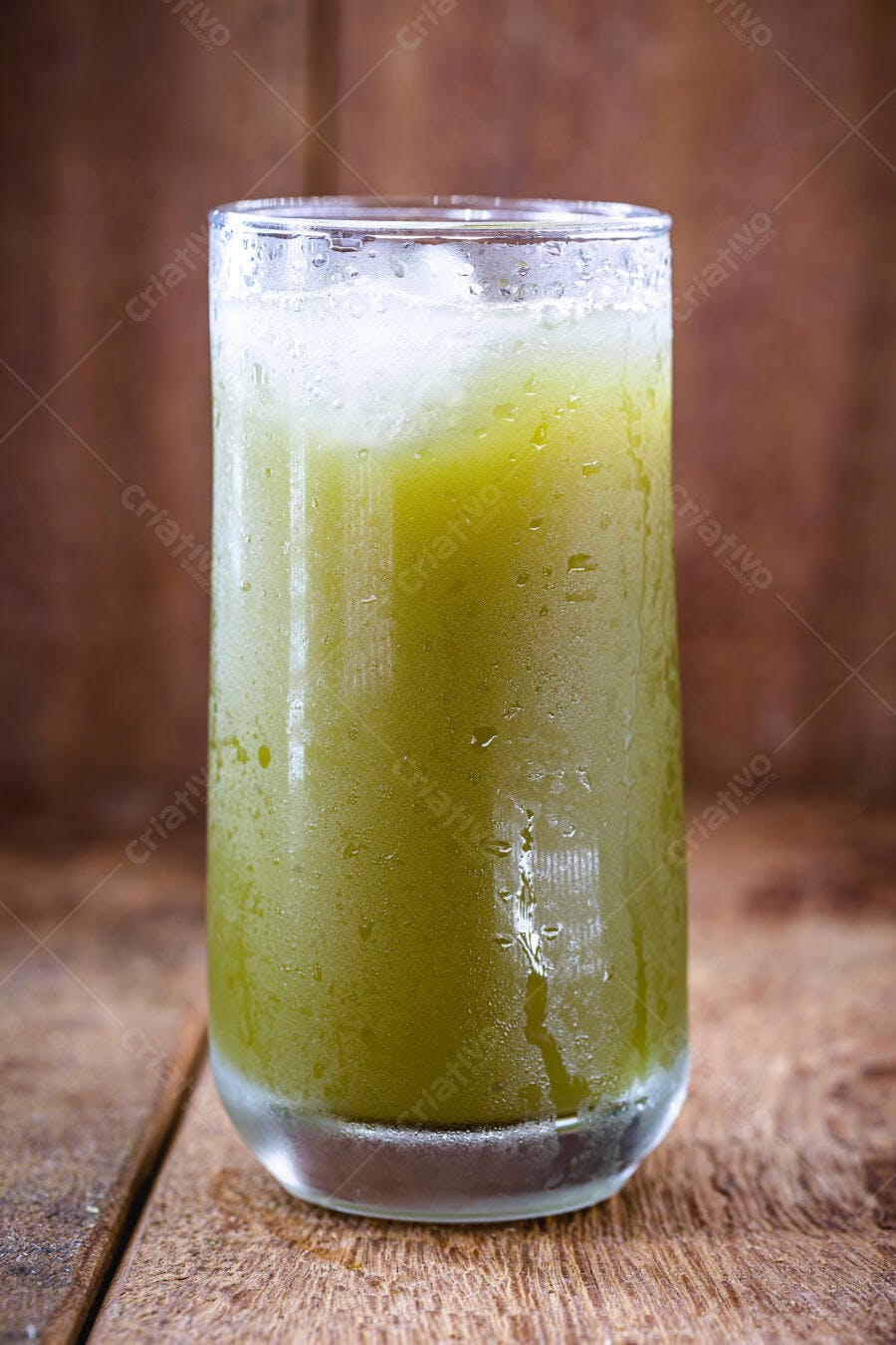 Copo de suco verde natural com gelo em mesa rústica de madeira
