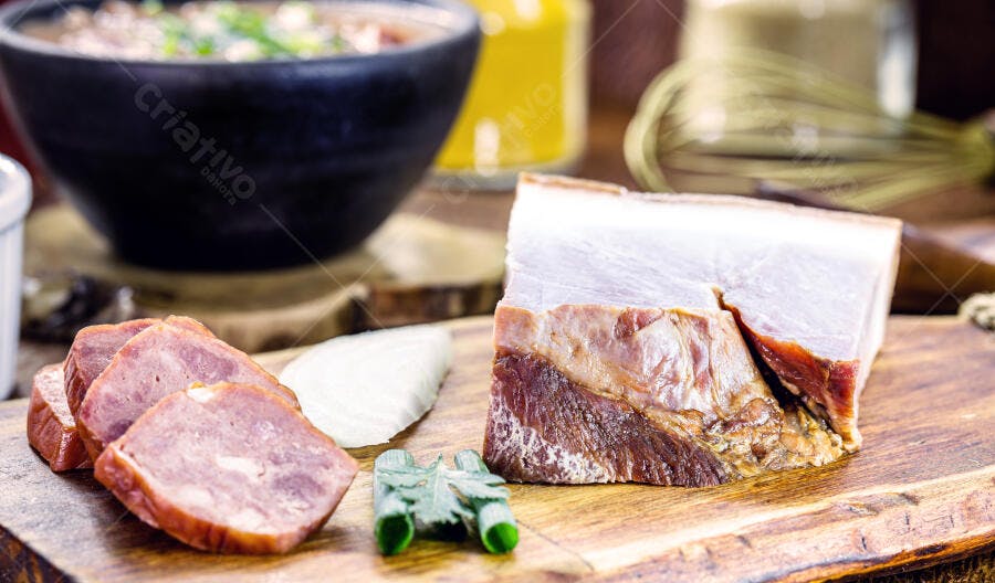 Ingredientes para feijoada panceta e linguiça fatiada em tábua de madeira rústica