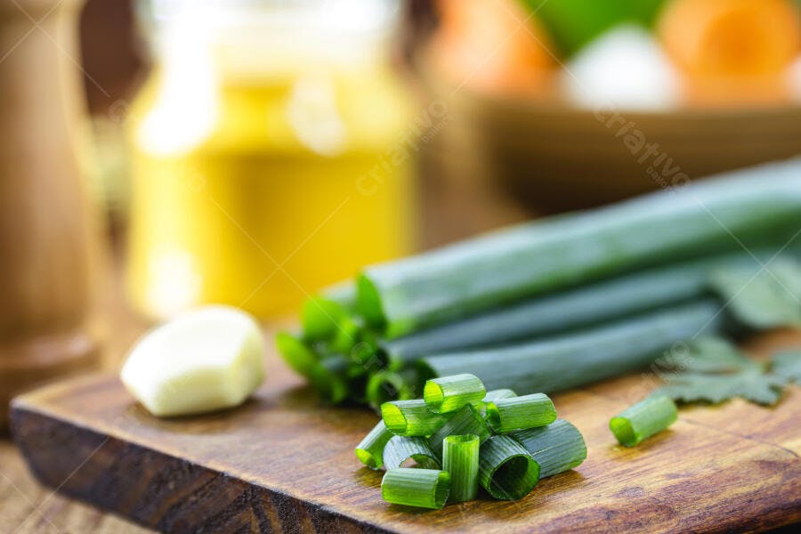 Cebolinha verde fresca picada na tábua de madeira com alho