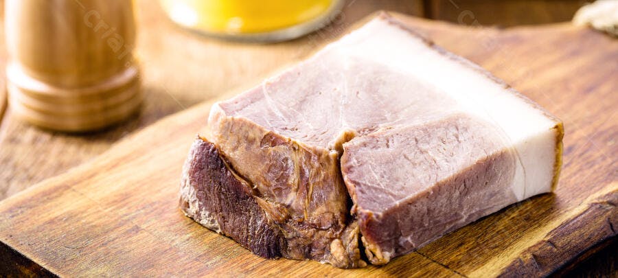 Bacon de porco defumado em bloco sobre tábua de madeira rústica marrom