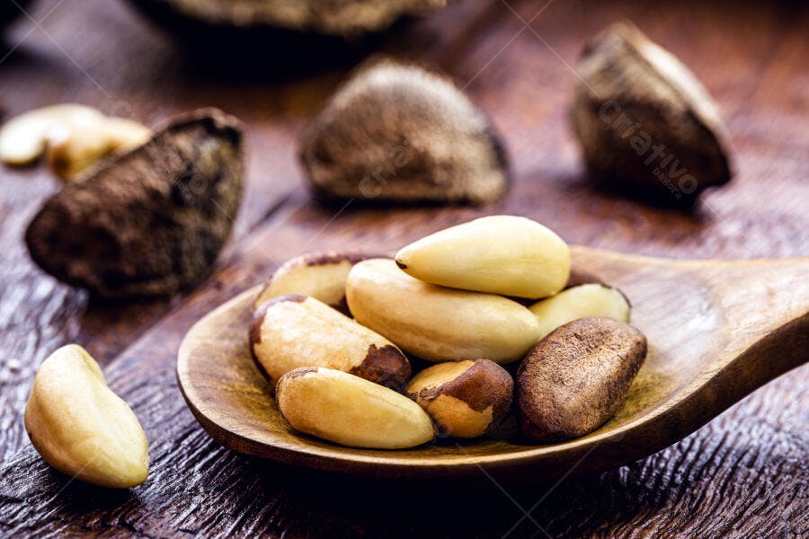Castanhas-do-Pará descascadas e com casca em colher de madeira rústica alimento saudável