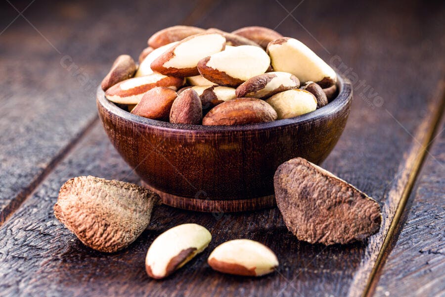 Castanhas-do-pará em tigela de madeira rústica descascadas e com casca