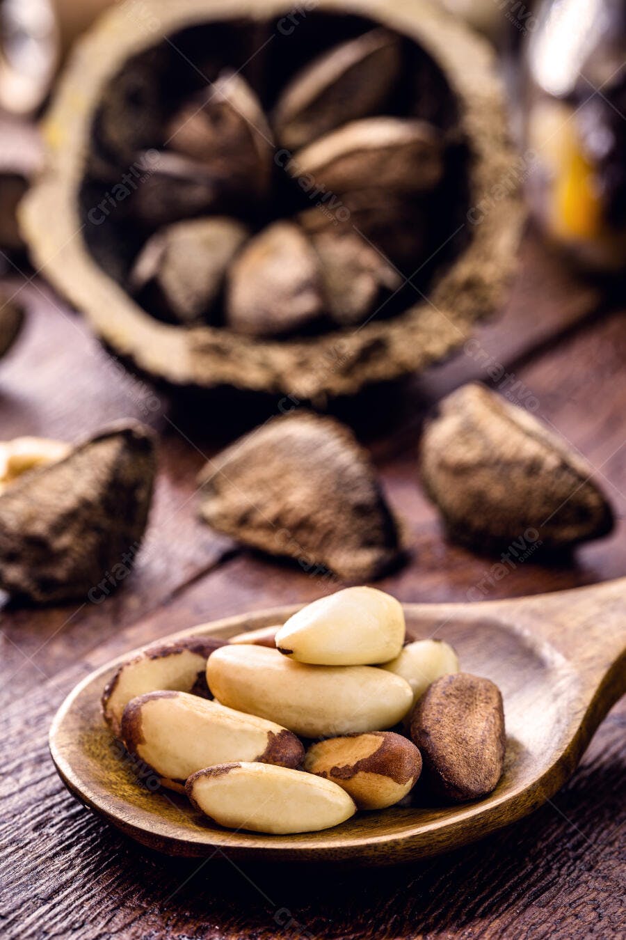Castanhas do Pará descascadas e com casca em colher de pau sobre madeira rústica