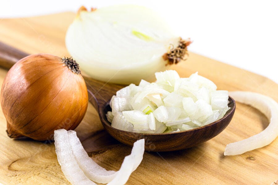 Cebola marrom e branca picada em tábua de madeira clara