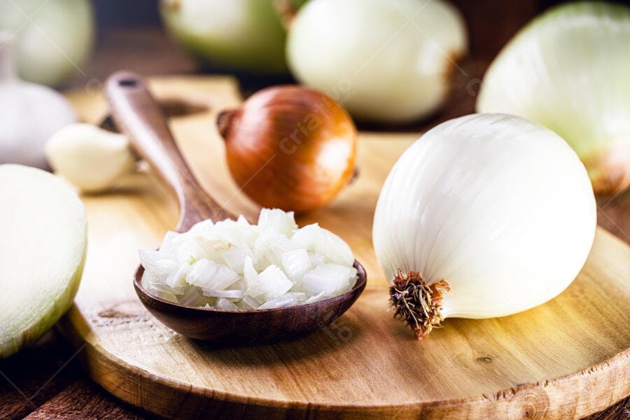 Cebolas frescas brancas e roxa com alho picado em colher de pau