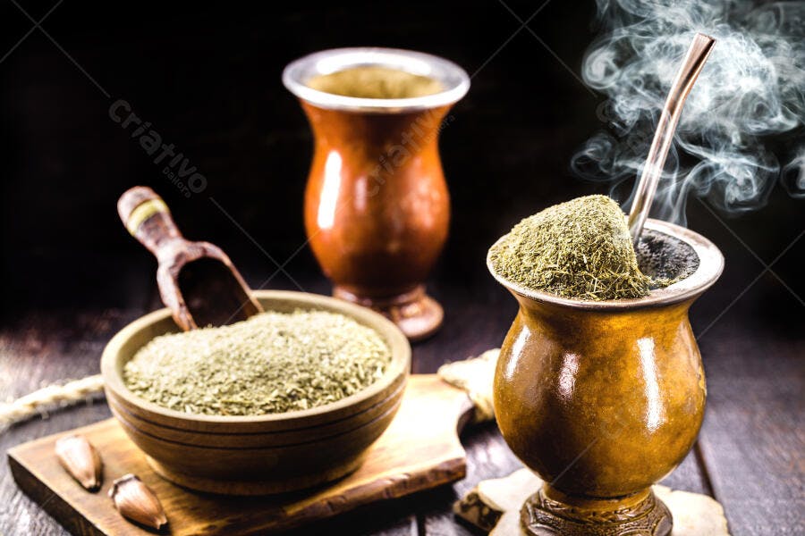 Chimarrão com vapor erva-mate cuia e pinhões em fundo escuro