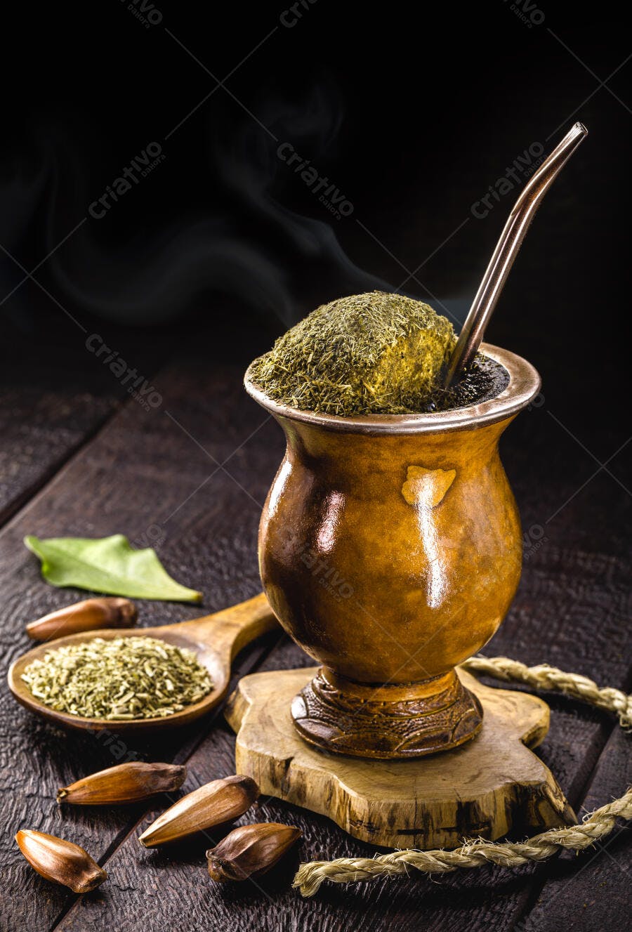 Chimarrão quente em cuia de madeira com erva-mate e pinhões em mesa rústica
