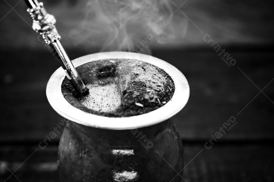 Chimarrão fumegante em cuia de madeira com bomba tradicional preto e branco