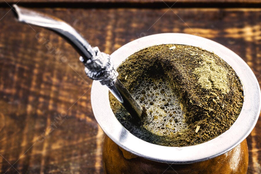Chimarrão tradicional em cuia de madeira com bomba de metal em fundo rústico