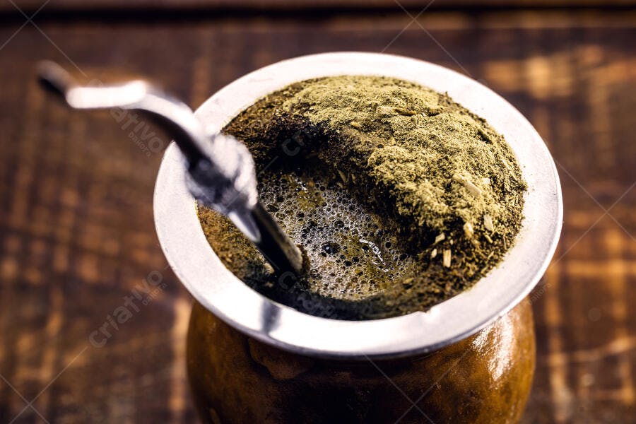 Chimarrão tradicional com erva mate verde na cuia sobre mesa de madeira escura