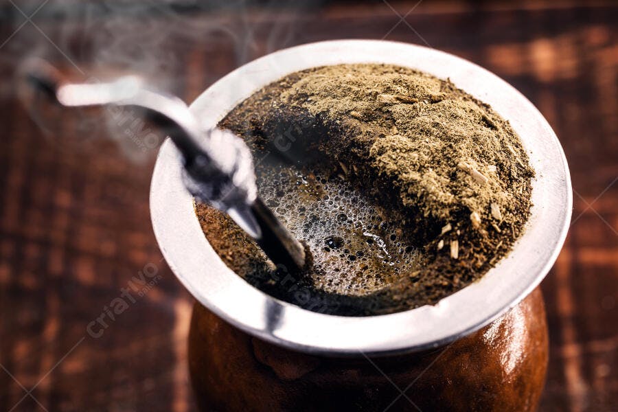 Chimarrão quente com erva mate e vapor em cuia tradicional sobre madeira
