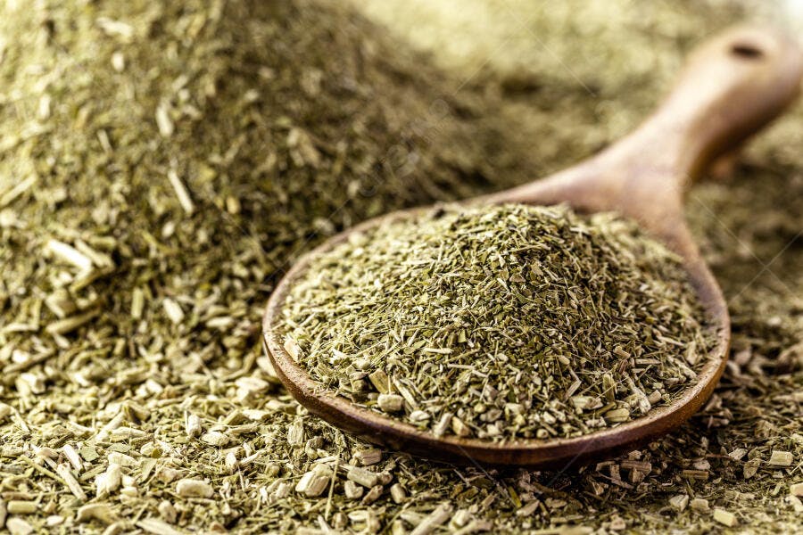 Erva-mate moída em colher de madeira rústica com fundo desfocado