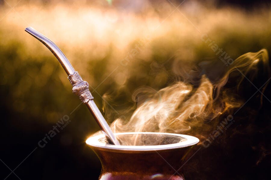 Cuia de chimarrão com bomba e vapor em fundo dourado aconchegante