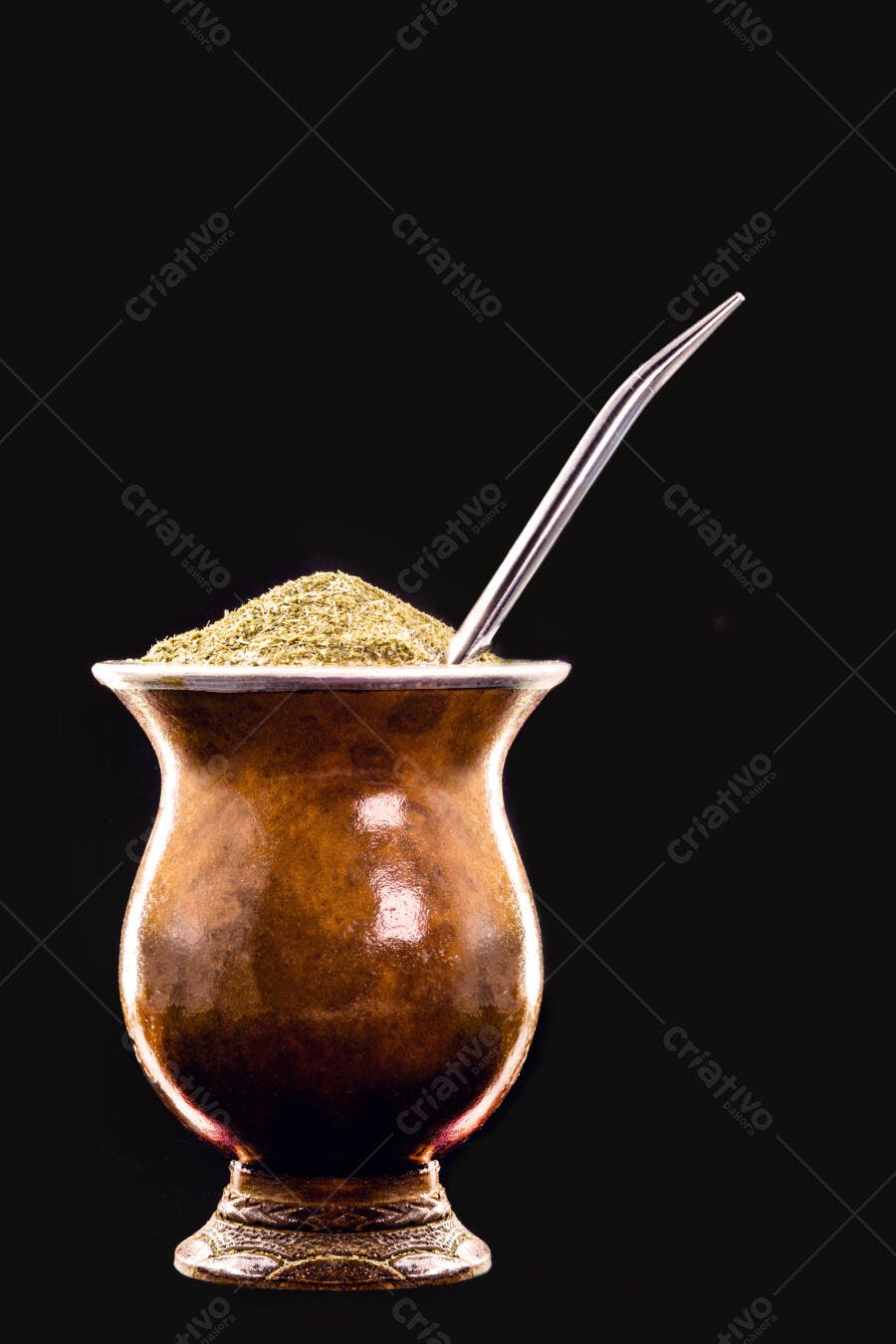 Cuia de chimarrão com erva mate verde e bombilla de metal em fundo preto