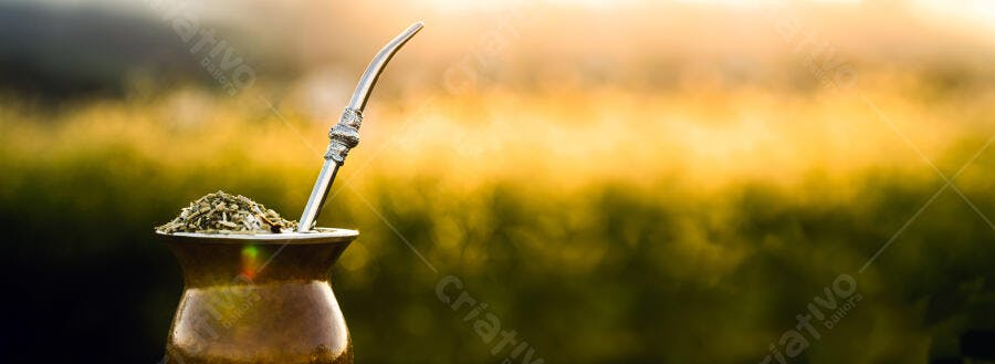Chimarrão com cuia e bomba em campo verde dourado ao entardecer