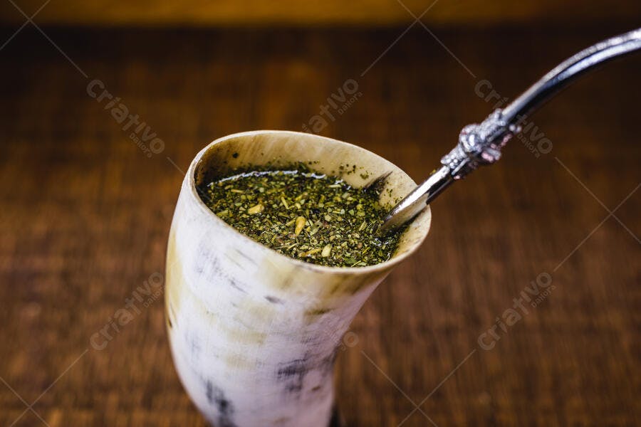 Guampa de tereré gelado com bomba de metal em mesa de madeira rústica