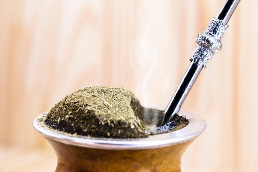 Chimarrão quente com erva-mate verde em cuia de madeira e bomba prateada