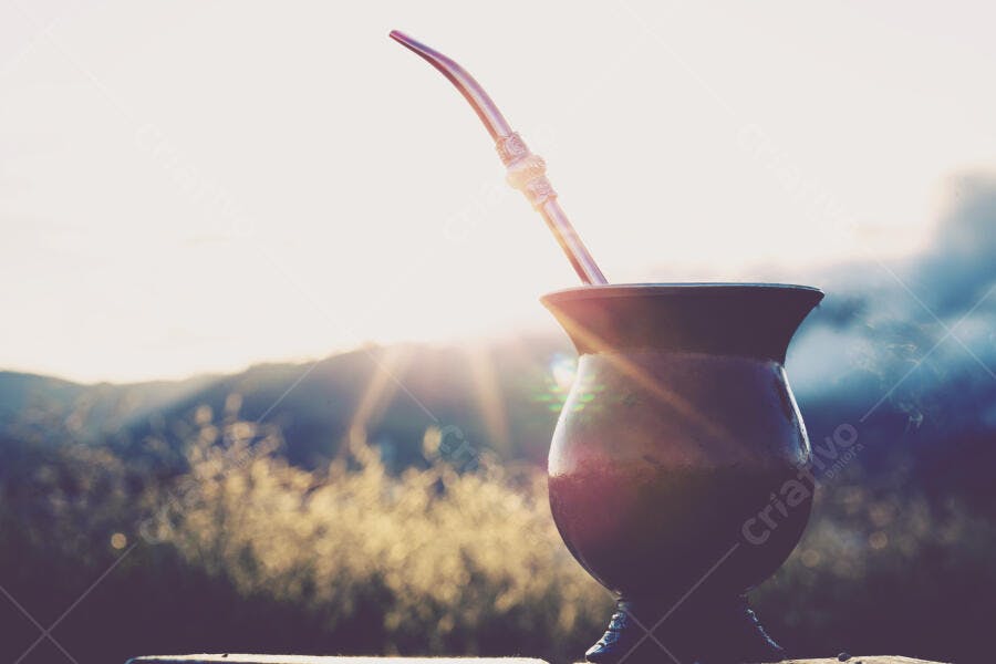 Mate tradicional com bombilla dourada em montanhas ao nascer do sol