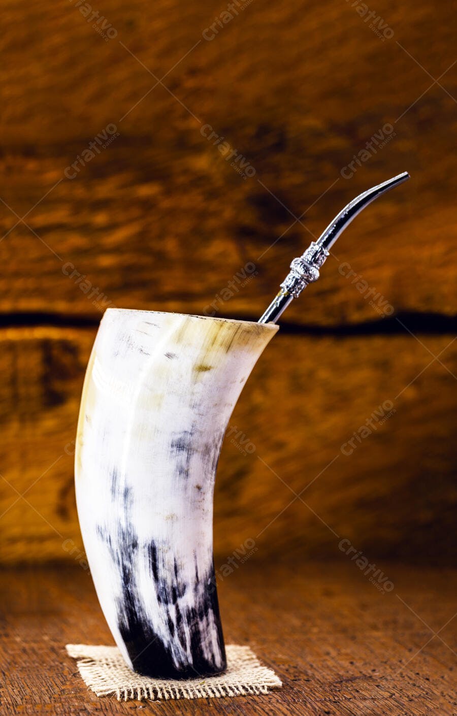 Guampa de chifre tradicional para tereré com bombilla de metal em fundo rústico