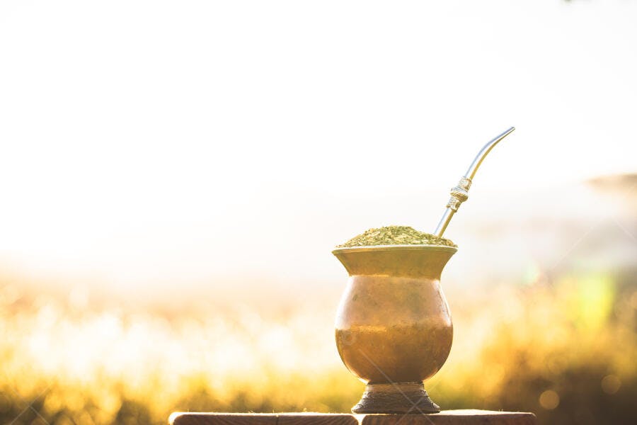 Mate tradicional cuia e bomba ao nascer do sol dourado em campo