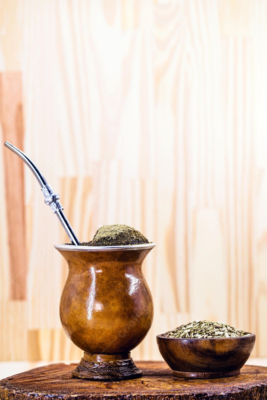 Chimarrão tradicional com erva mate na cuia e bomba em fundo de madeira claro