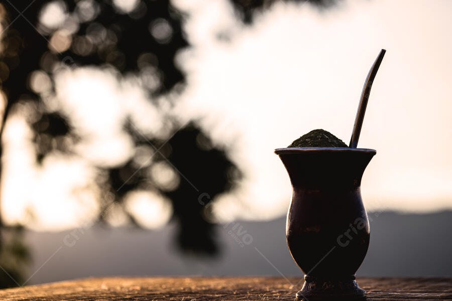 Cuia de mate com erva-mate e bombilla silhueta ao pôr do sol nas montanhas