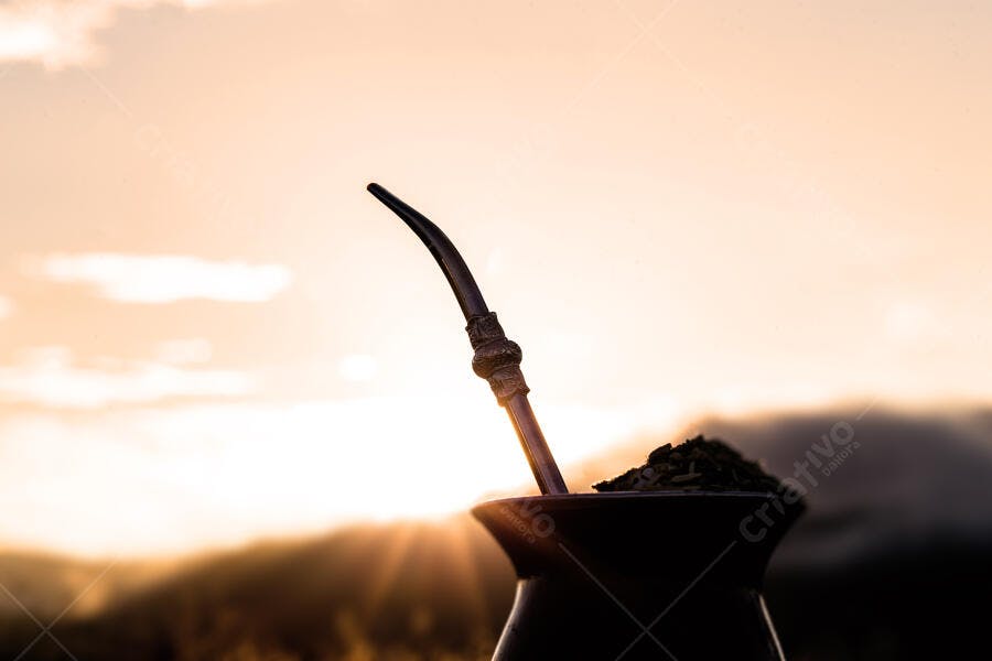 Chimarrão com pôr do sol dourado em paisagem rural montanhosa