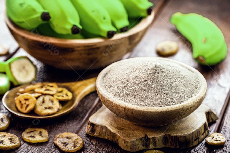 Farinha de banana verde e bananas frescas em tigelas sobre madeira rústica