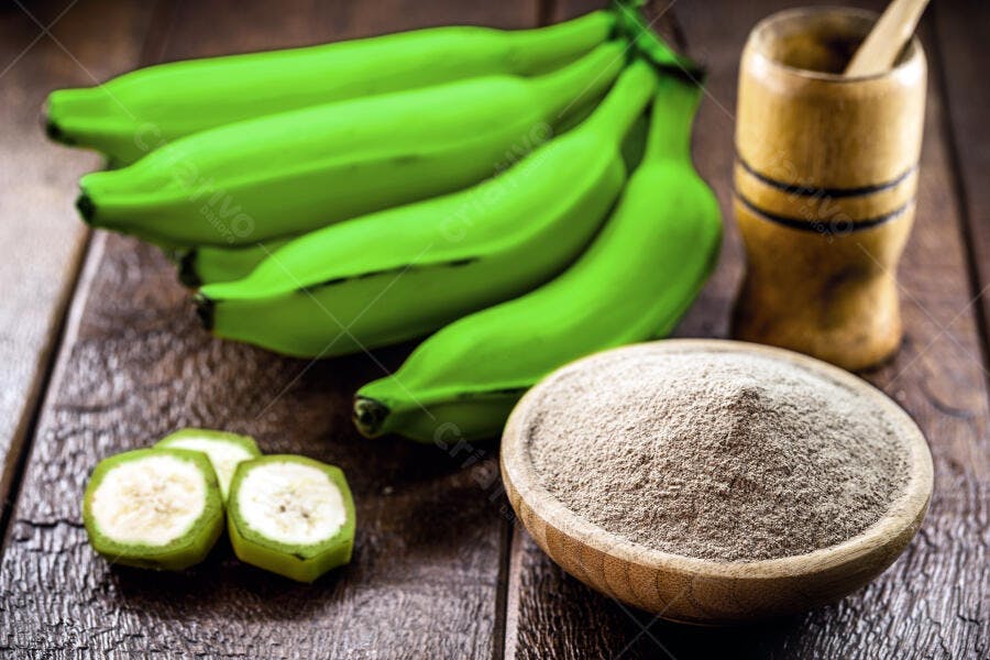 Bananas verdes e farinha de banana em tigela de madeira rústica