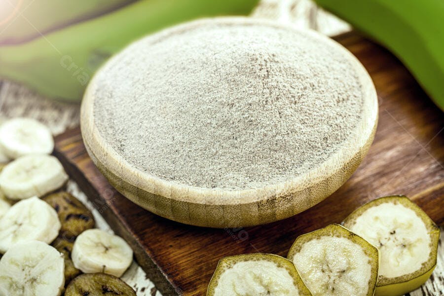 Farinha de banana verde em tigela de madeira com rodelas frescas e maduras