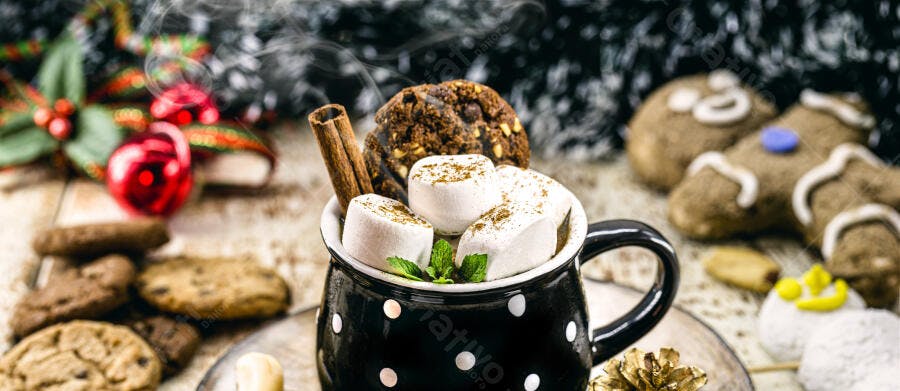 Caneca de chocolate quente com marshmallows canela e biscoitos de Natal em mesa de madeira