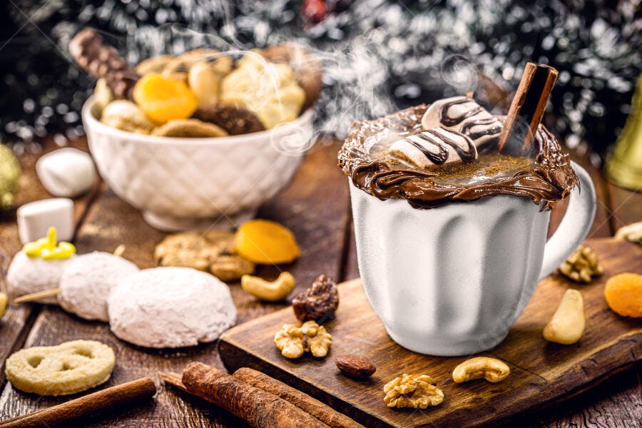 Caneca branca de chocolate quente com marshmallows e canela fumegante em cenário festivo