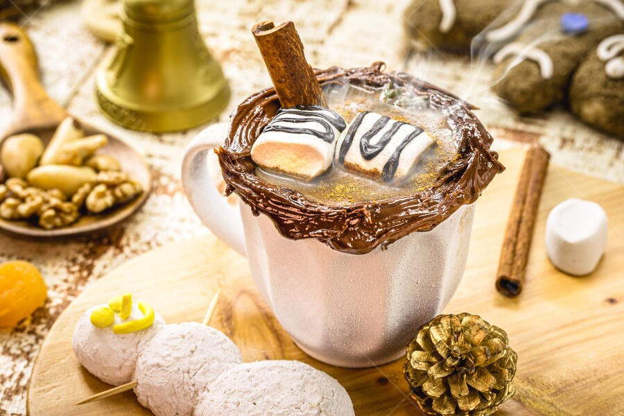 Chocolate quente com marshmallows canela e calda em cenário natalino aconchegante