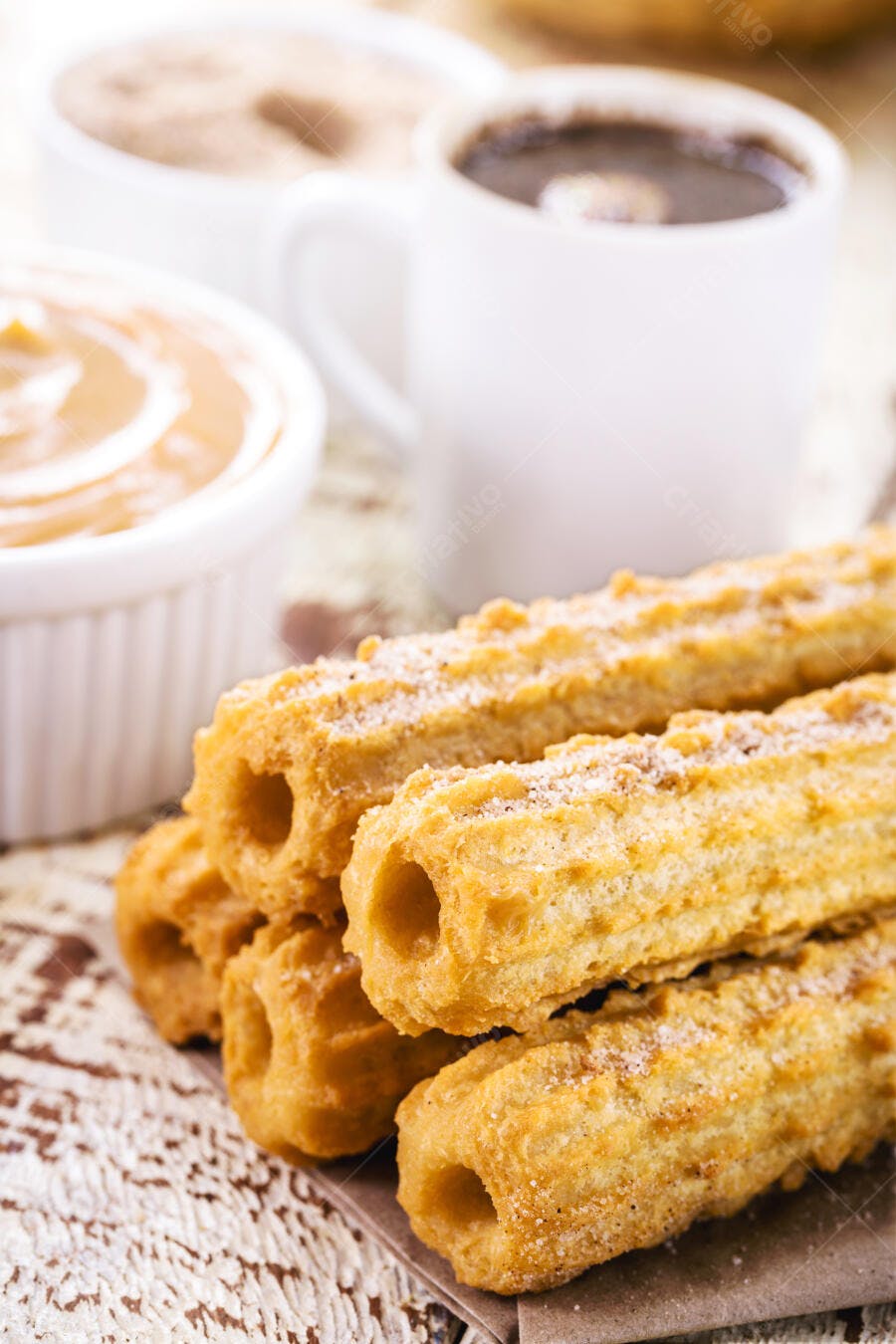 Churros crocantes com açúcar e café em mesa rústica