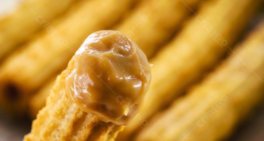 Churro crocante com doce de leite cremoso sobre fundo desfocado