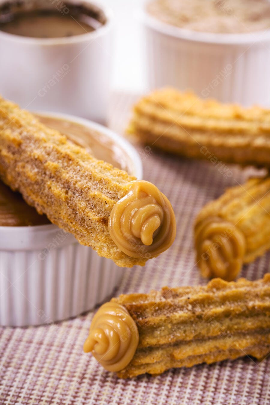 Churros dourados com doce de leite caramelo em tigelas brancas