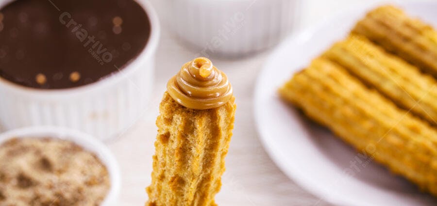 Churro dourado com doce de leite e molho de chocolate sobre a mesa