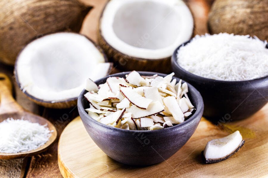 Lascas de coco ralado e fruta fresca em tigelas rústicas de madeira